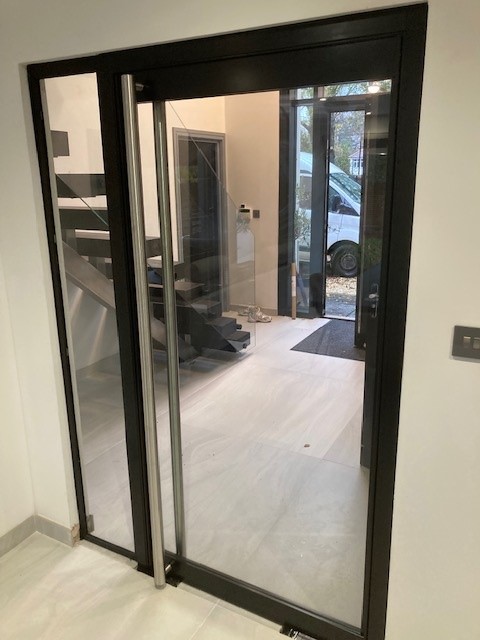Open black-framed glazed door with full-height fixed glass side panels