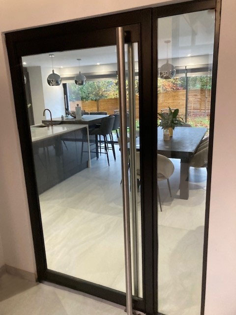 Black steel-framed glazed door within a larger internal glass screen
