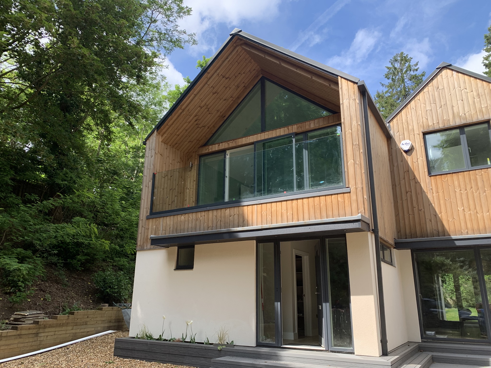 Completed bespoke glass balustrade — clean frameless panel on upper floor of timber home