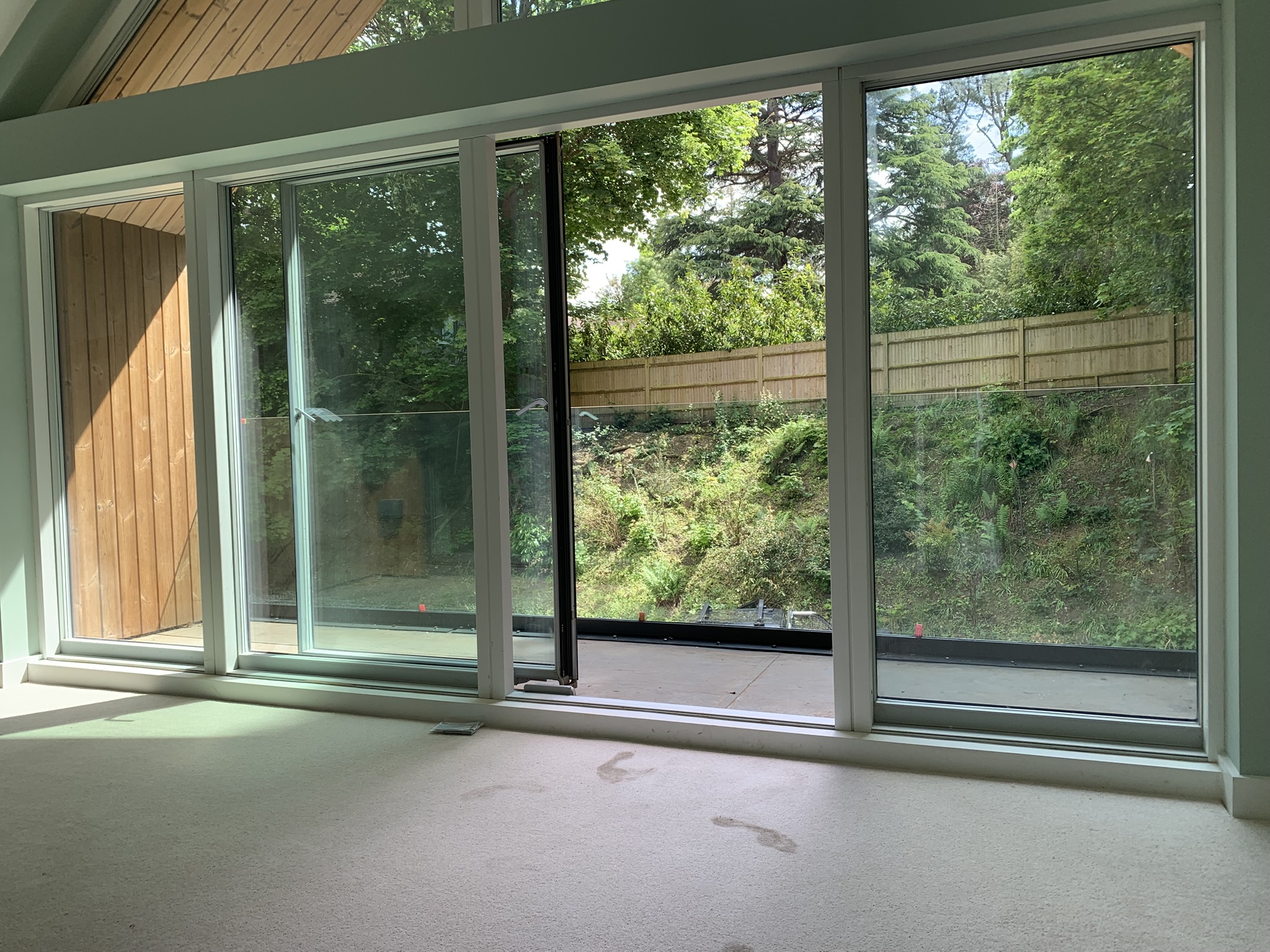 Interior view from the bedroom — large floor-to-ceiling glazing and glass balustrade at Henley-on-Thames timber home