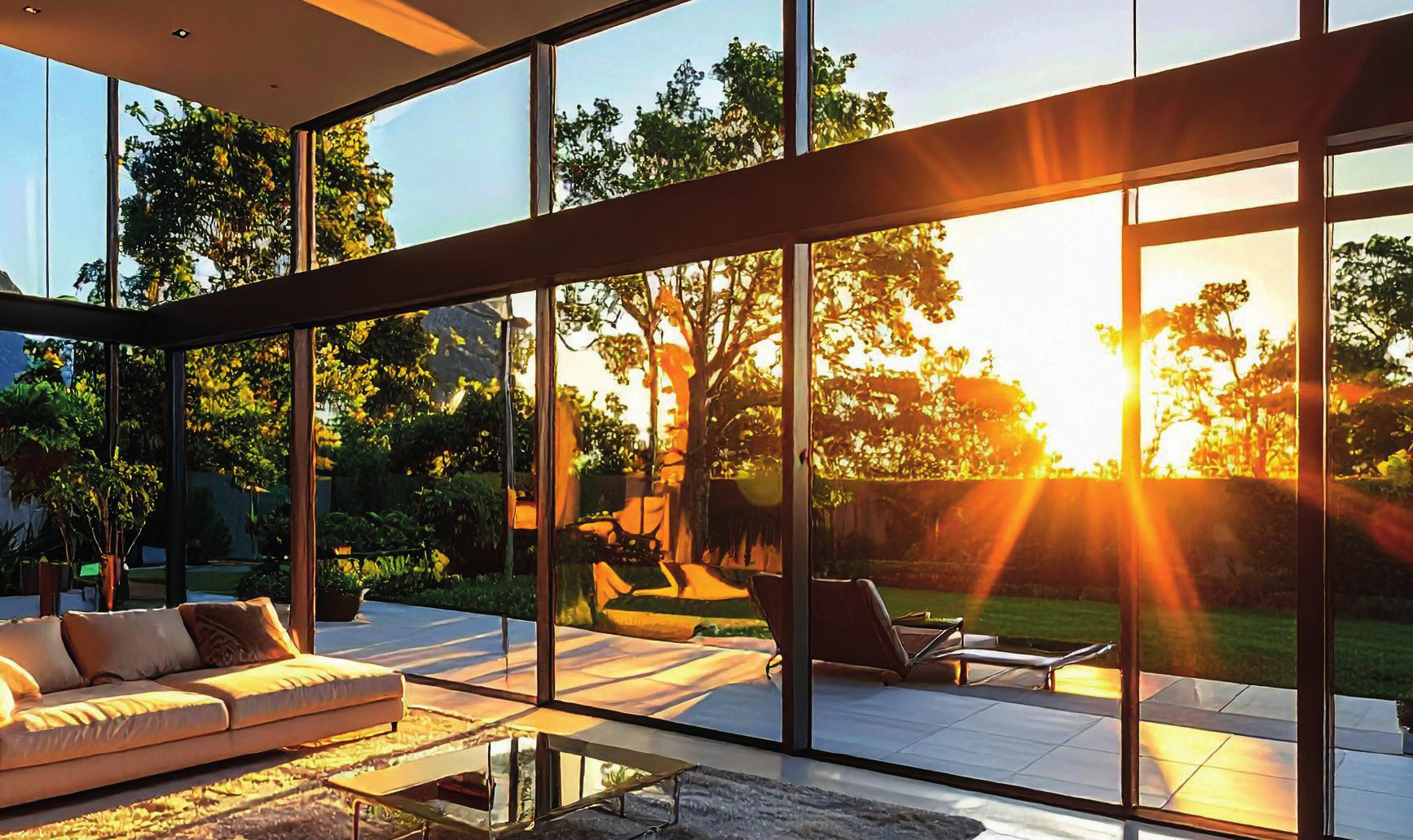 Open-plan living space with large glazed walls in strong sunlight